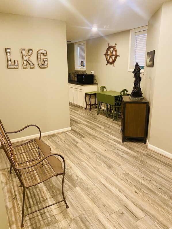 A living room with a wooden floor, a green dining table, and a metal chair.