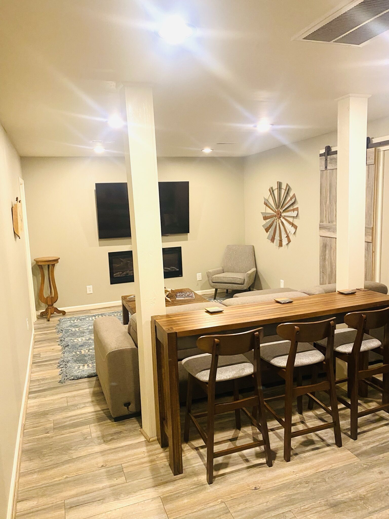 A dining area with a wooden table and chairs, a sofa, and a decorative windmill on the wall.