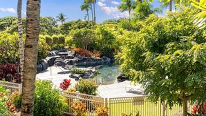 A tropical garden with a pool, surrounded by palm trees and various plants. - Hilton Pool Pass  for stays in 2026. Waikoloa Beach Villas C23 (Waikoloa Beach Resort)