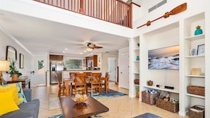 A spacious living room with a high ceiling, a dining area, and a kitchen. - Hilton Pool Pass  for stays in 2026. Waikoloa Beach Villas C23 (Waikoloa Beach Resort)