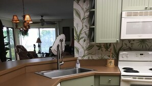 A kitchen with green cabinets, a white stove, and a wooden countertop.