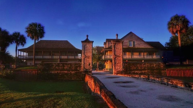 A historic building with a central courtyard, stone pillars, and a gated entrance.