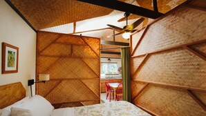 Una habitación con una cama, ventilador de techo y vista a un área de cocina.