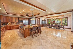 A spacious kitchen with a large island, wooden cabinets, and a dining area with a view of the outdoors.