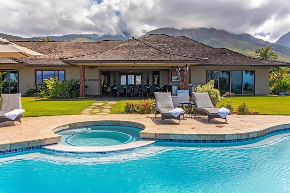 A hotel with a swimming pool, lounge chairs, and a restaurant.