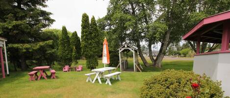 A picnic area with tables and chairs, a gazebo, and a rose bush.