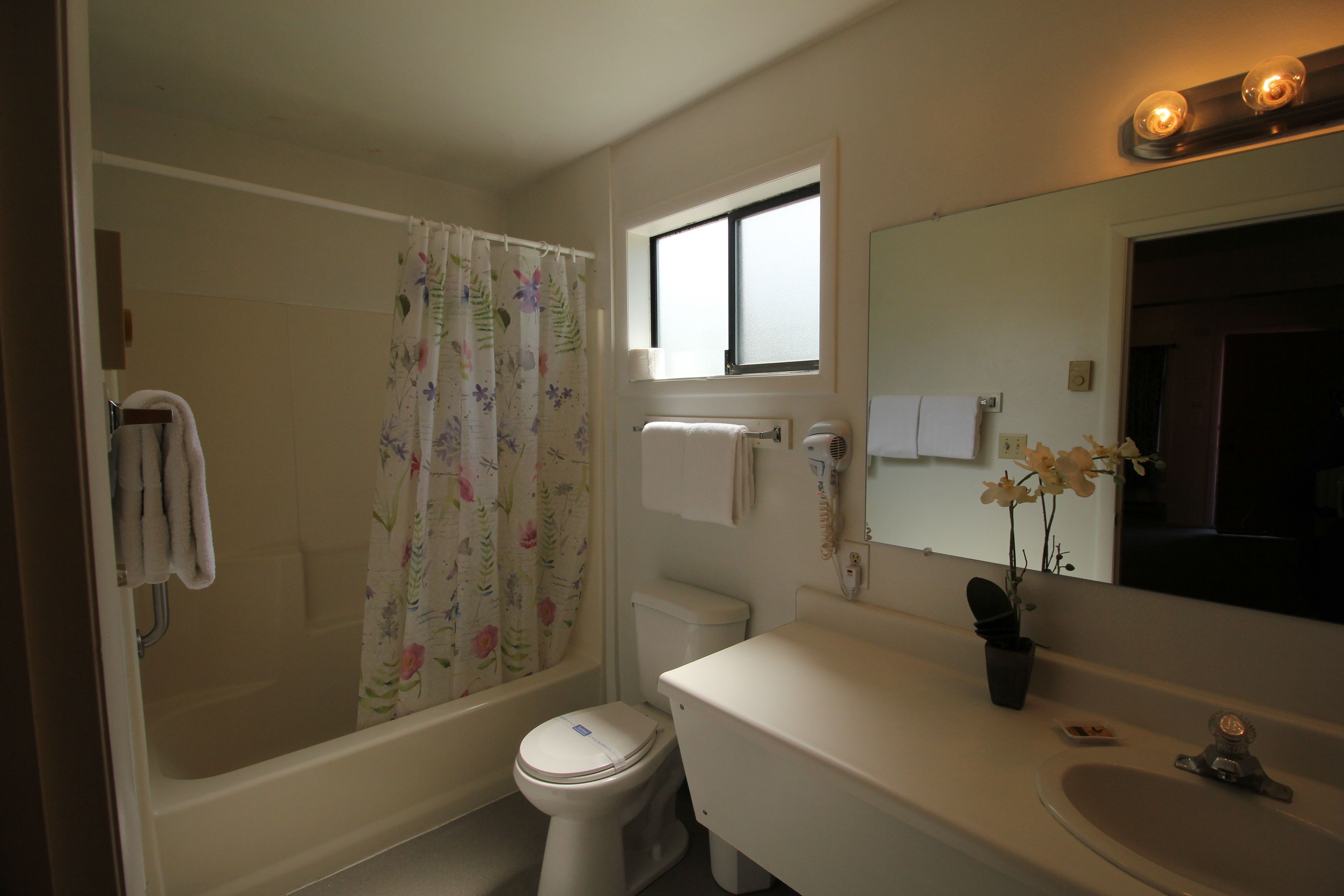 Un baño con bañera, inodoro, lavamanos y ventana.