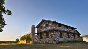 Une maison en pierre avec un grand silo en arrière-plan.