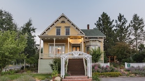 Una casa de dos pisos con un porche, un letrero que dice "The Richardson House", y una valla blanca que rodea la propiedad.