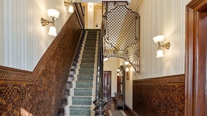 Una imponente escalera con barandillas ornamentadas y alfombra estampada que lleva a una plataforma.