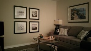 A living room with a sofa, a coffee table, and four framed pictures on the wall. - New Construction Coach House, 10 Minute Walk to Downtown and Ferry Spotless (Nanaimo)