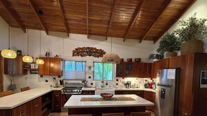 Eine moderne Küche mit Holzausstattung, einer zentralen Kochinsel und Pendelleuchten.
