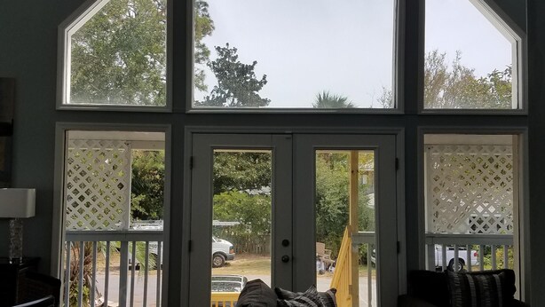 Ett rum med ett stort takfönster, en takfläkt och utsikt över omgivningen.