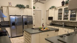Cocina moderna con armarios blancos, electrodomésticos de acero inoxidable y una isla central con frutas frescas.