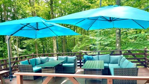 An outdoor deck with a wooden railing, a sofa set, and two blue umbrellas providing shade. - Treasure Lake Vacation Rental (Sleeps 16!) (Du Boise)