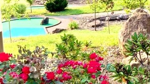 A landscaped garden with a swimming pool, a large rock, and red flowers in the foreground. - Treasure Lake Vacation Rental (Sleeps 16!) (Du Boise)