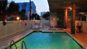A swimming pool with a wooden deck, a white fence, and a sign indicating no diving.