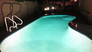 A swimming pool with a curved edge and a white metal ladder.