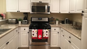 A kitchen with white cabinets, a stainless steel stove, a microwave, and a toaster.