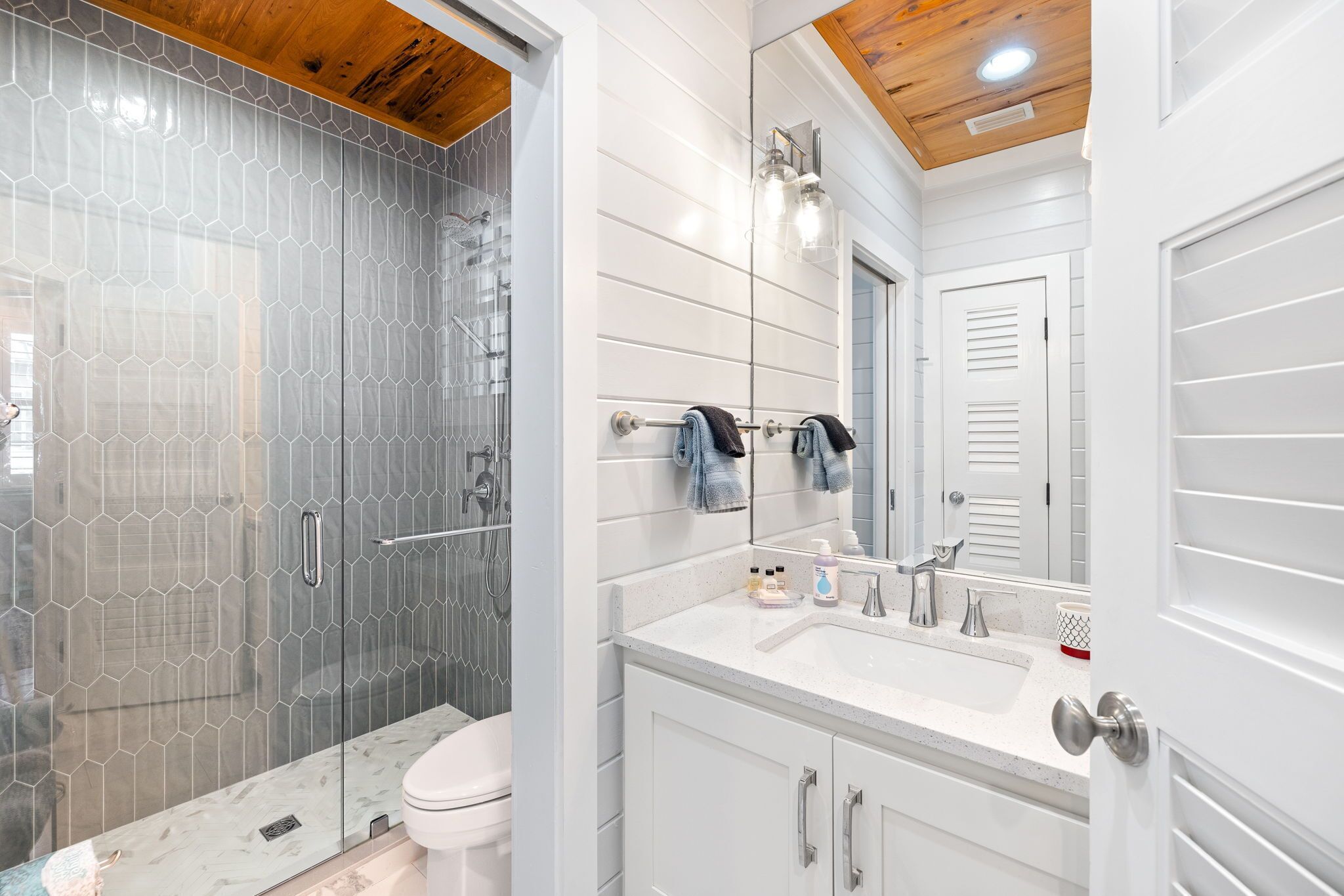 A modern bathroom with a glass shower enclosure, a white vanity with a sink and mirror, and a toilet.