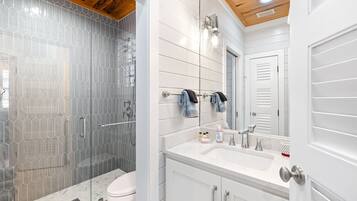 A modern bathroom with a glass shower enclosure, a white vanity with a sink and mirror, and a toilet.