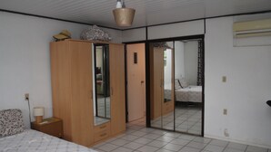 Ein Schlafzimmer mit Bett, Kleiderschrank, Spiegel und einer Schiebetür zu einem weiteren Raum.