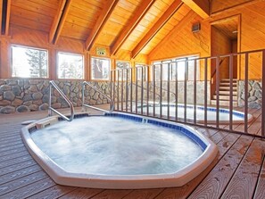 Relax by the oval-shaped pool surrounded by a stone wall and metal railing.
