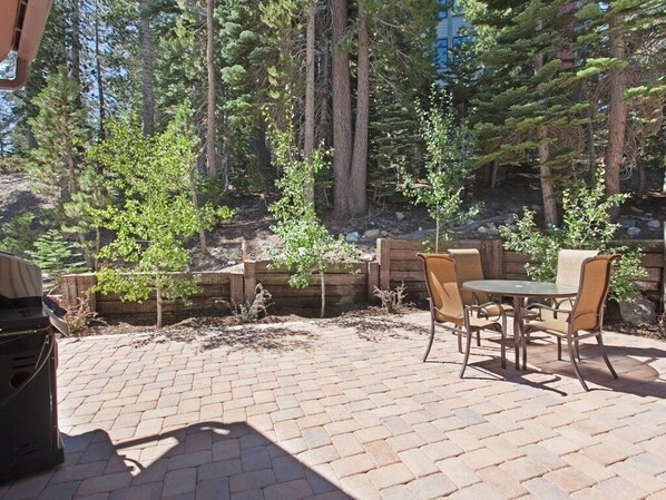 An outdoor patio with brick flooring, a grill, and a table with chairs. - Steps to Canyon Lodge! Luxurious Fully Updated, 2 Bedroom 2 Bath Condo W/Garage (Mammoth Lakes)