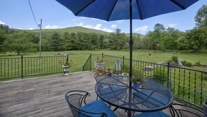 A wooden deck with a table and chairs, surrounded by a metal fence and potted plants. - Windham/Hunter All-season French Country Farmhouse-Moments Away from Hayfield. (Maplecrest)