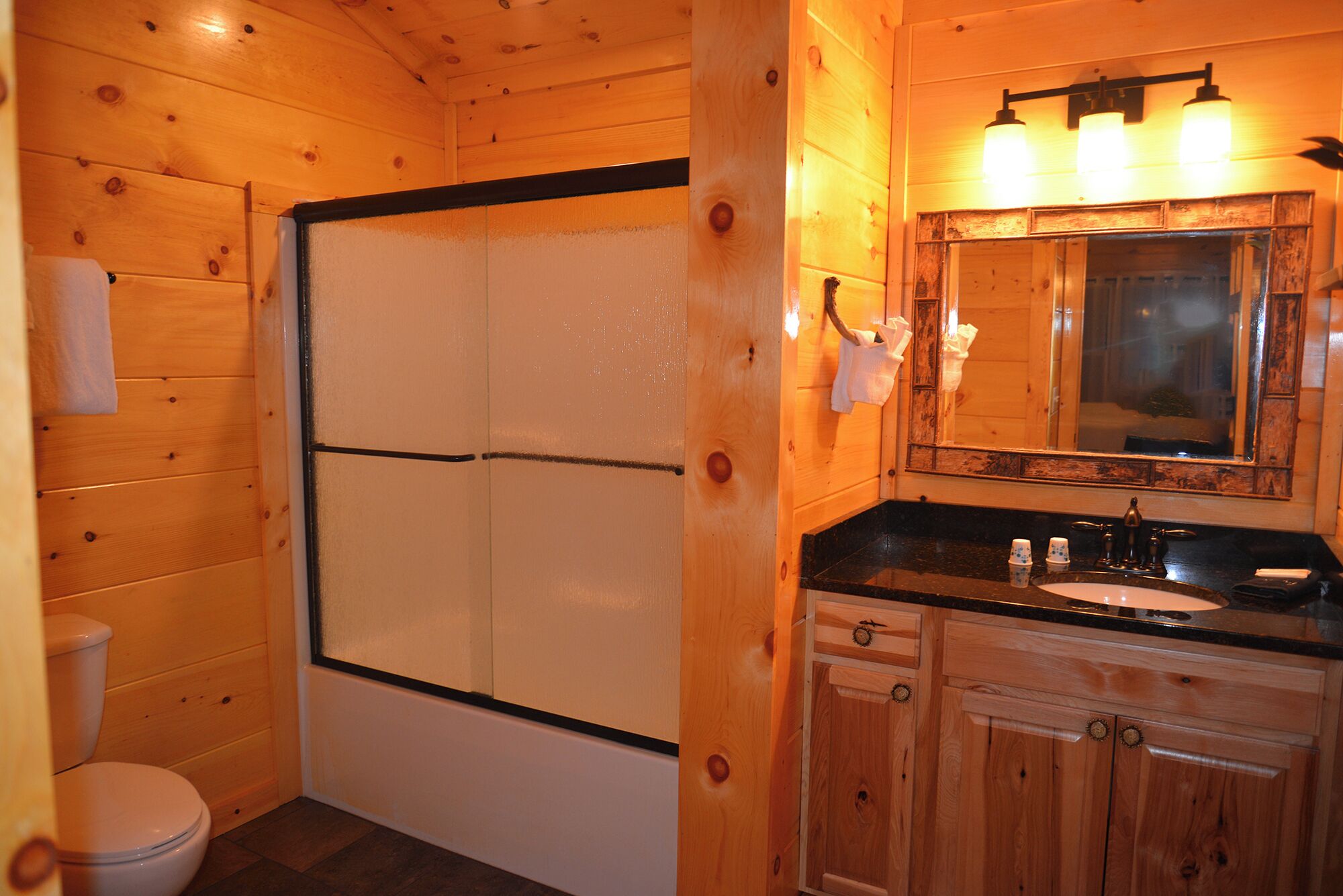 Un baño de madera con ducha, inodoro, lavabo y tocador.