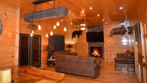 Un intérieur chaleureux de chalet en bois avec une cheminée, des canapés en cuir et un coin repas.