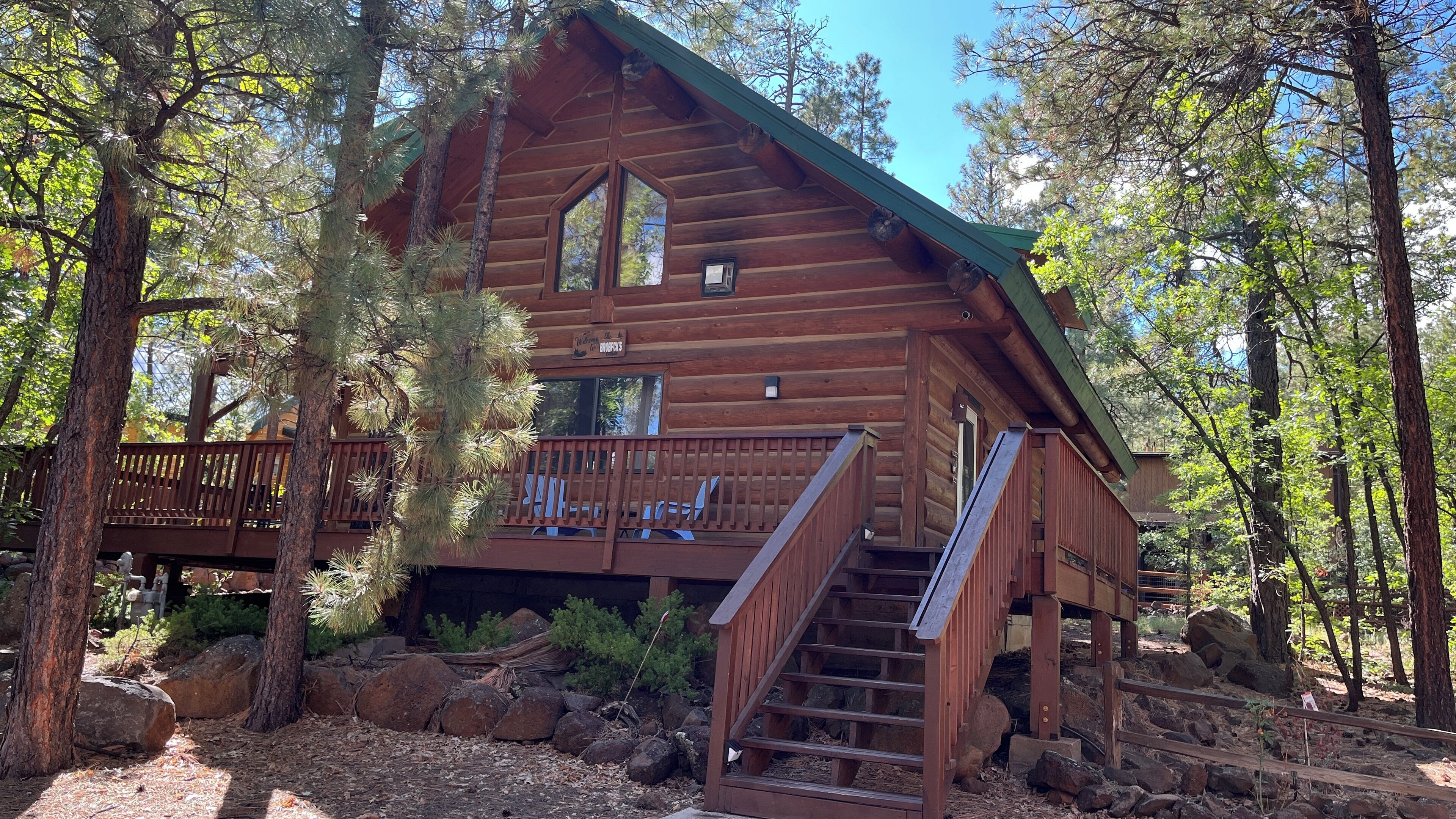A log cabin with a wooden deck and a staircase leading to the entrance.