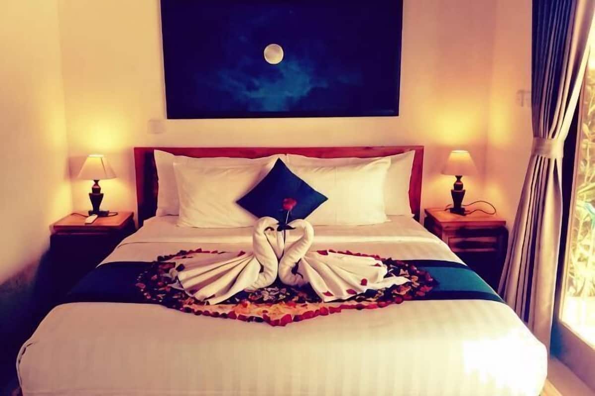 A hotel room with a bed, two bedside tables with lamps, a painting on the wall, and a window with curtains.
