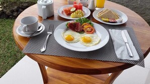 A breakfast setup with eggs, toast, and juice on a table with a view of a rice field. - Paraiso Cottage Ubud (Ubud)
