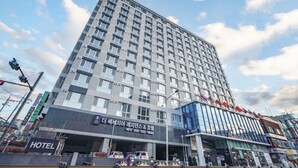 A modern hotel building with multiple floors, a prominent entrance, and a visible parking area. - The Venezia Suite Hotel (Chuncheon)