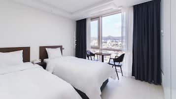 A hotel room with two beds, a small table, and a chair.