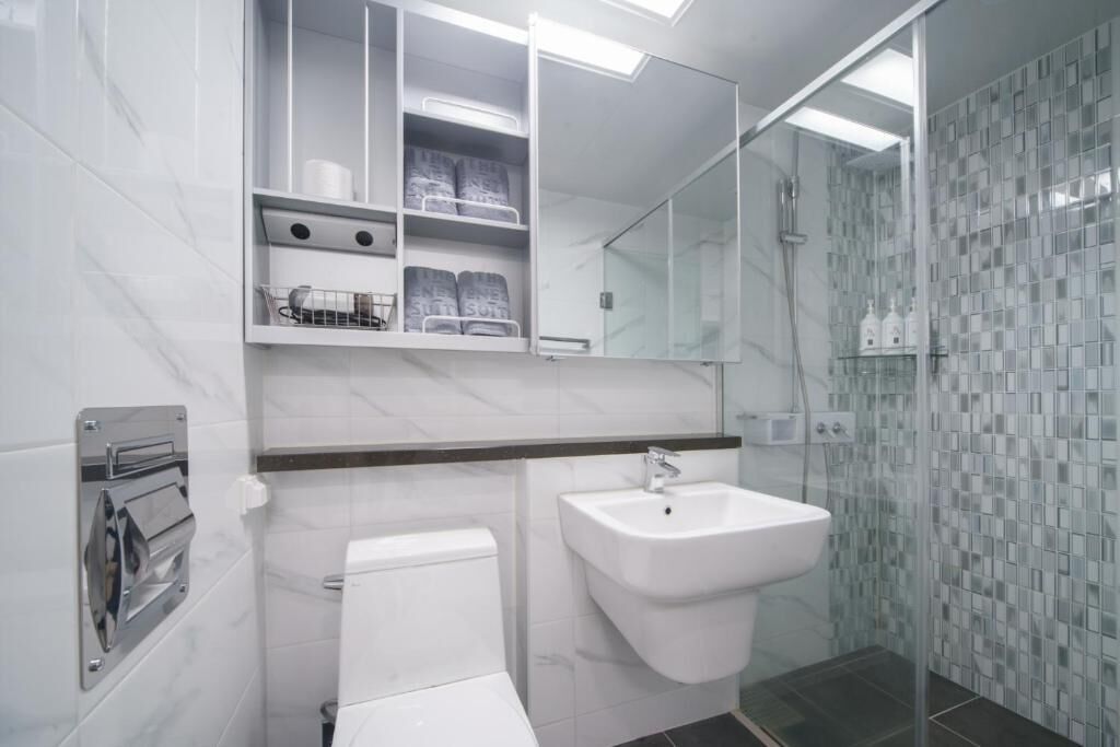 A modern bathroom with a toilet, sink, and glass shower enclosure.
