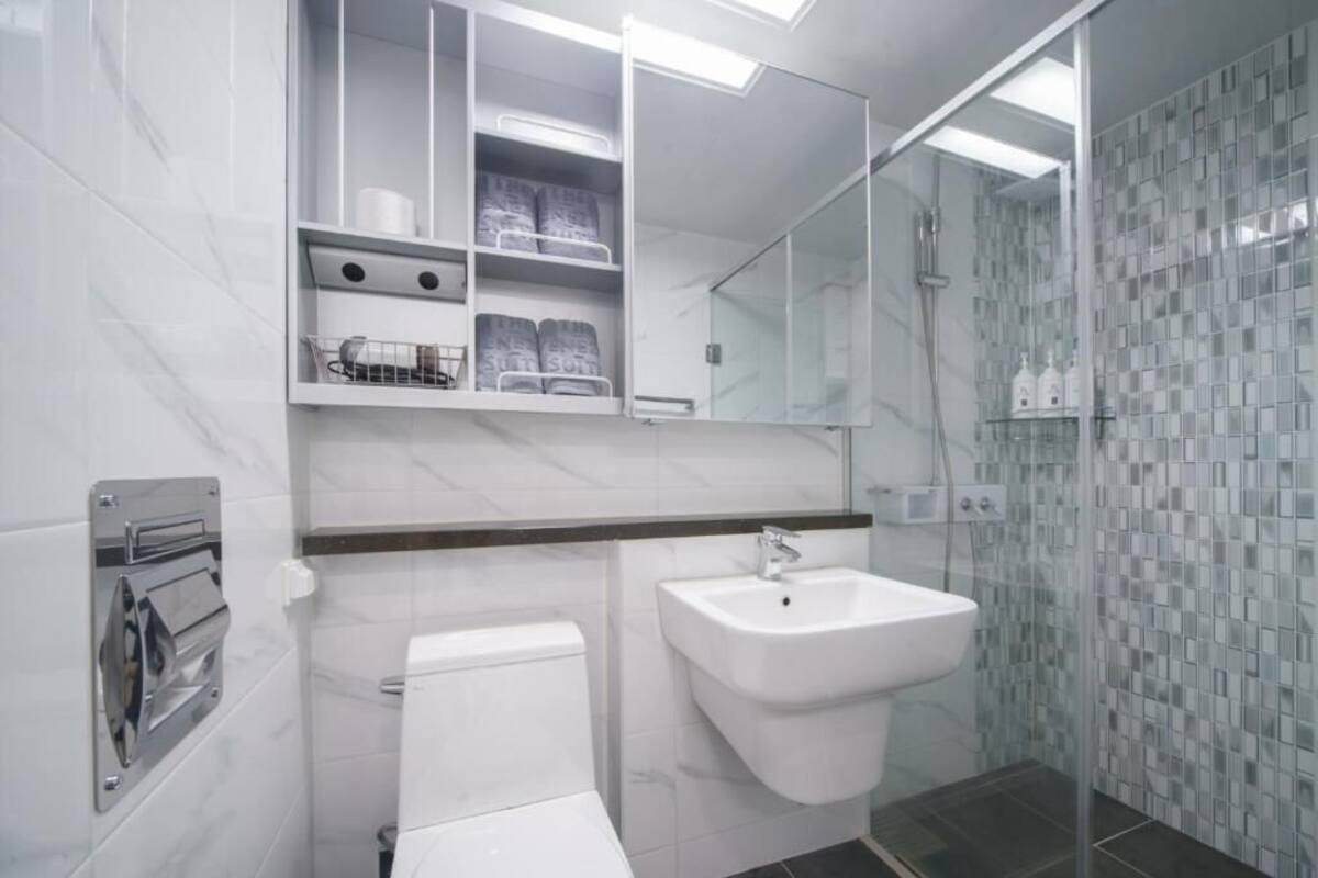A modern bathroom with a toilet, sink, and glass shower enclosure.