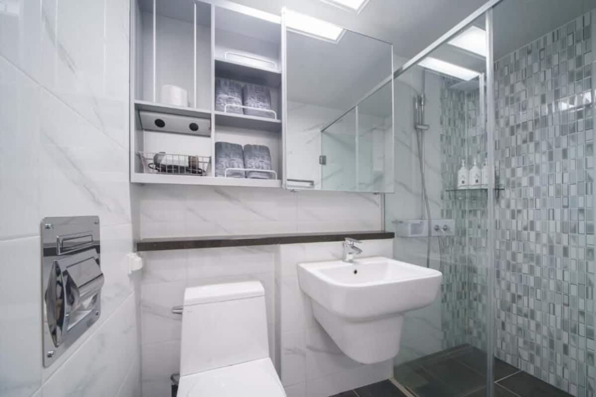 Uma casa de banho moderna com sanita, lavatório e cabine de duche em vidro.