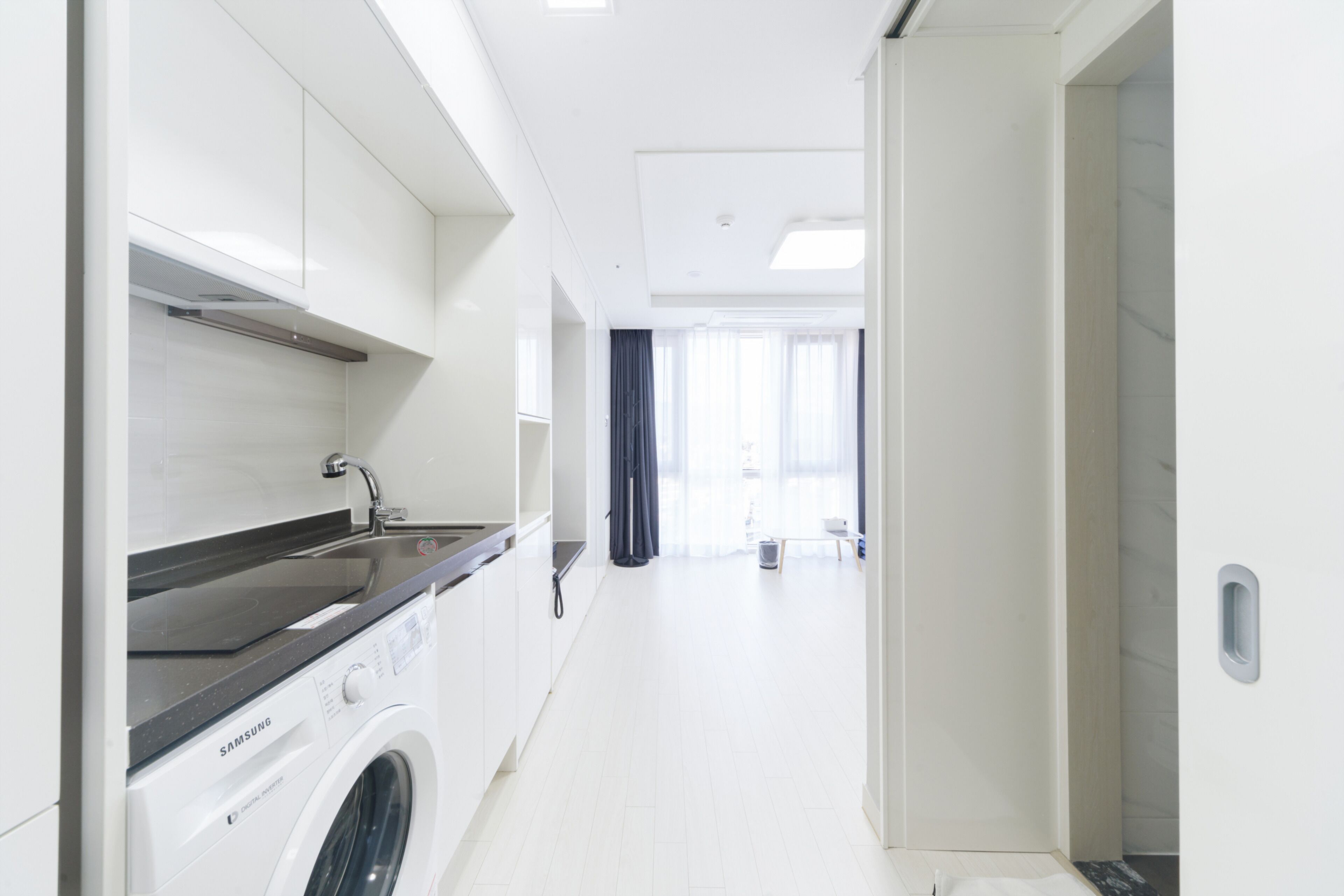 Una cocina moderna con lavadora y secadora integradas, un ventanal y vistas al salón.