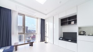 A modern, bright living room with a large window, a bench, and built-in kitchen cabinets. - The Venezia Suite Hotel (Chuncheon)