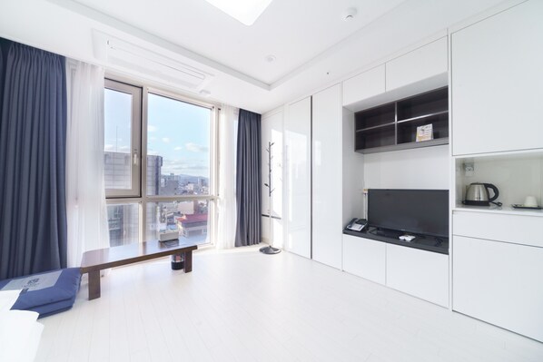 Una sala de estar moderna y luminosa con un gran ventanal, un banco y armarios de cocina empotrados.