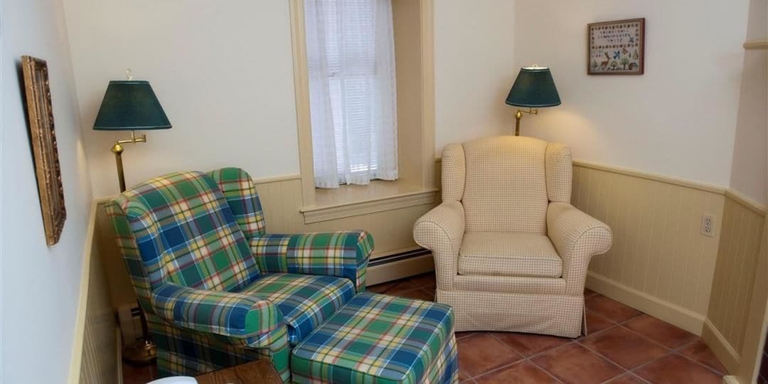 A room with two chairs, one plaid and one checkered, and two lamps.
