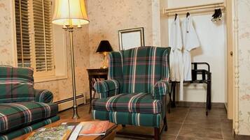A room with a plaid sofa, a matching armchair, a floor lamp, and a small table with a magazine.
