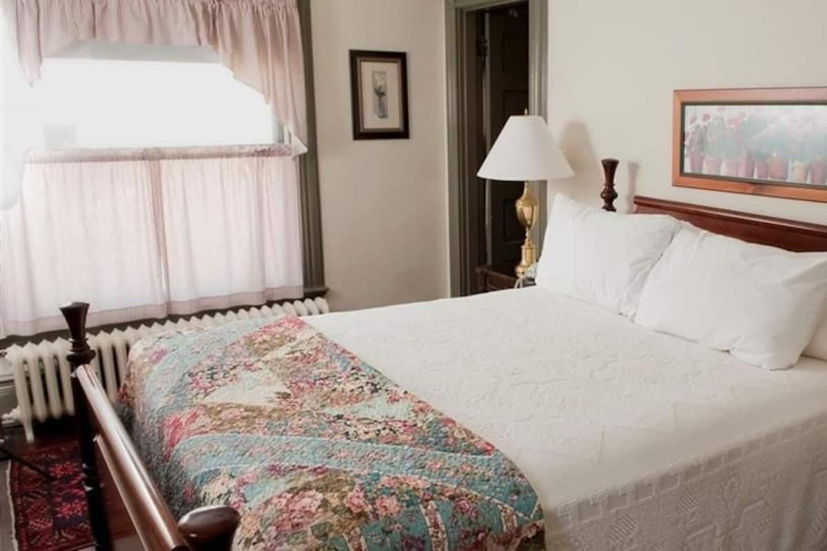 A neatly made bed with a floral bedspread, a wooden headboard, and two bedside lamps.