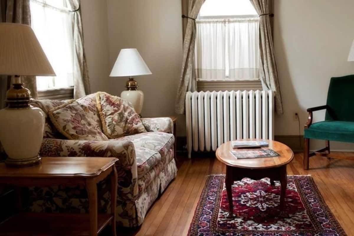 A living room with a sofa, a coffee table, a green armchair, and two lamps.
