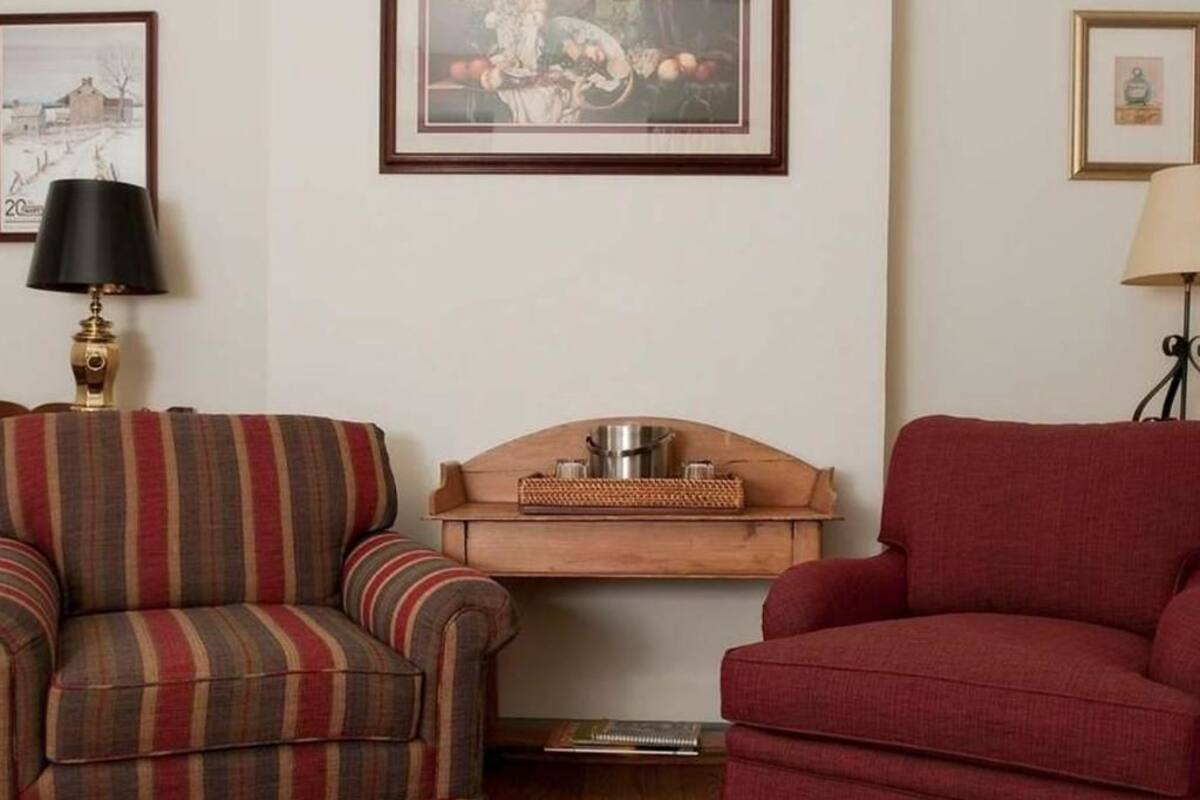 A living room with striped and solid red sofas, a wooden sideboard, and framed artwork on the walls.