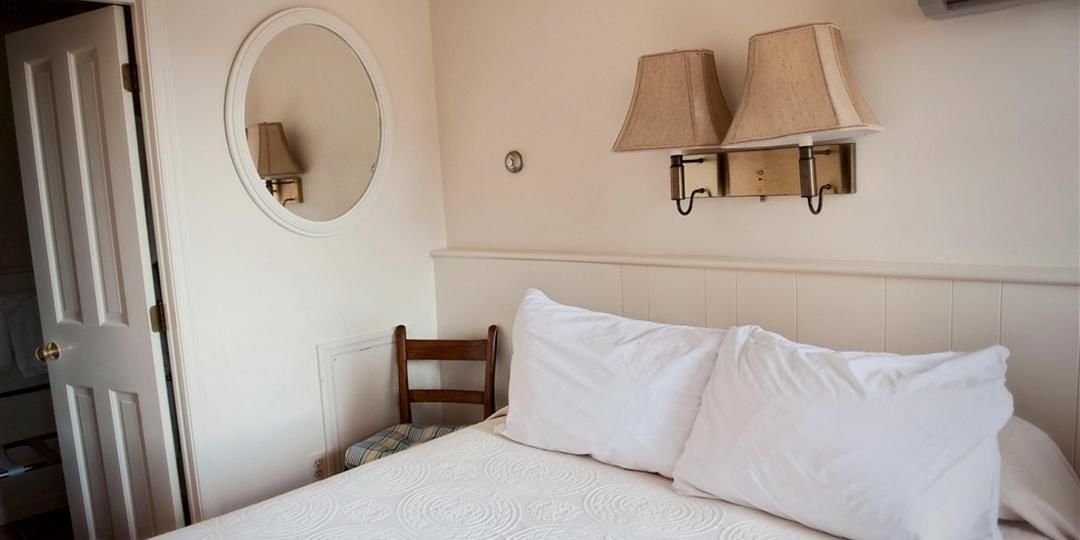 Ein Hotelzimmer mit einem Bett, einem Sessel, einem runden Spiegel und zwei Wandlampen.