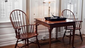 Una mesa de comedor con dos sillas de madera, una bandeja con un tazón y vasos, y una lámpara.
