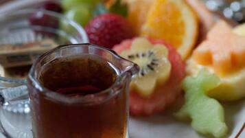 A glass pitcher of tea, a plate with sliced fruits, and a small dish with a chocolate bar.